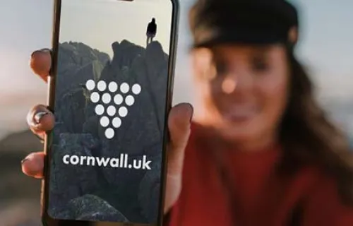 woman holding mobile showing cornish ambassador logo