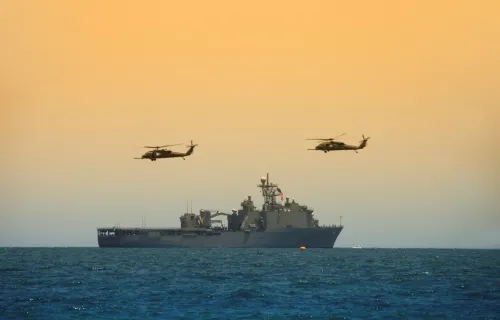 Helicopters hovering over a Navy battleship at sea