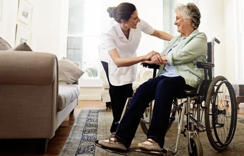 Kuvituskuva: sairaanhoitaja auttaa pyörätuolissa olevaa naista. 