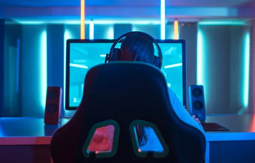 Ryggen av en kvinna i gaming stol framför en dator
