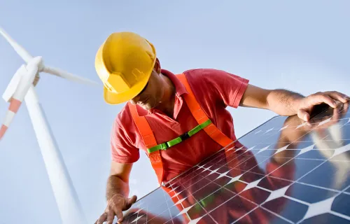 Kuvituskuva: työmies asentaa aurinkopaneeleja