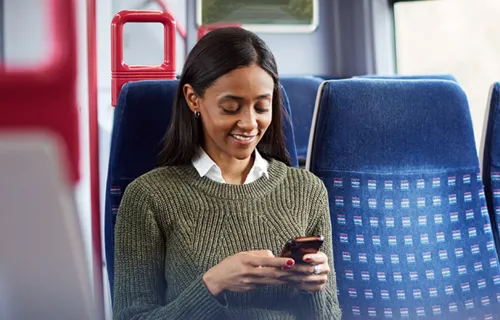 A woman using her mobile phone while seated inside the train