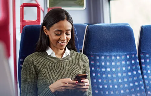 Female sat on public transport looking at her mobile phone 