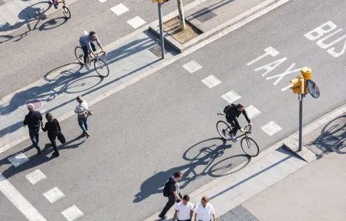 People using the pedestrian crosswalk on a busy street
