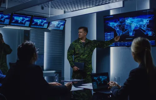 defence professionals discuss a map on a display screen