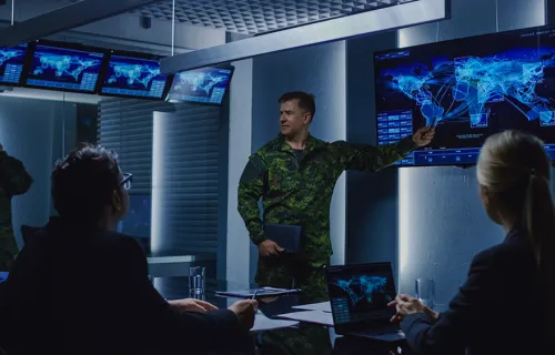 People discuss a map displayed on a screen in a mission control room