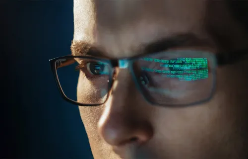 Computer codes reflecting on a person’s eyeglass. 