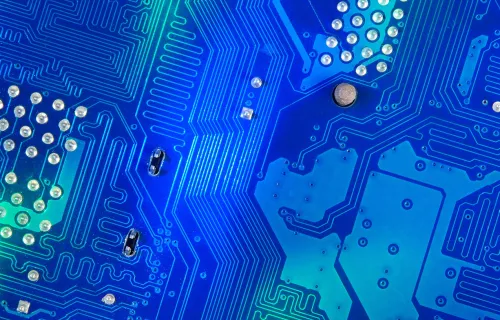 Nærbilde av blått kretskort med ledningsbaner og komponenter.