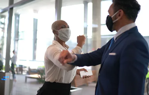 Colleagues elbow bumping in masks as they discuss CGI ROSO