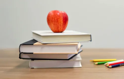Omena ja koulukirjoja pinossa