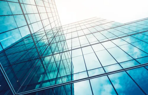 Moderni lasirakennus, jonka heijastavat pinnat muodostavat abstraktin, verkostomaisen rakenteen.