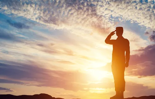 saluting soldier silhouetted in sunrise