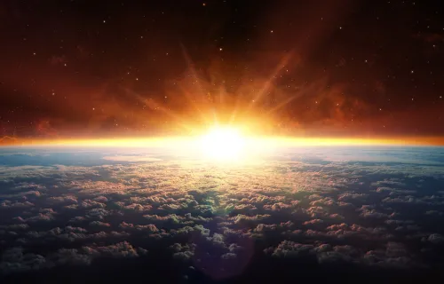 Soluppgång sedd från rymden med jorden och dess molntäcke i förgrunden. Solljuset bryter fram…