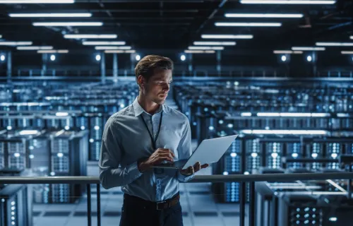 Technologist standing using a laptop in a server room