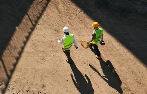 Top view of builders in hardhats and green safety jackets at a construction site