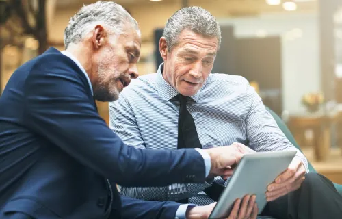 Two businessmen discussing info on a tablet
