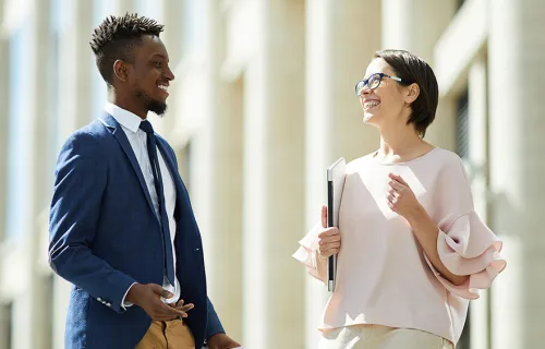 Kvinnlig och manlig kollega står utanför kontoret och samtalar glatt