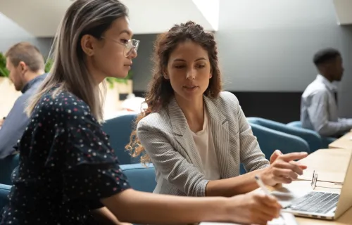 two people speaking in front of laptop