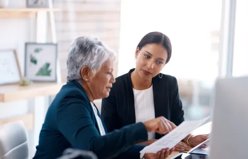 Two professionals seated reviewing a document