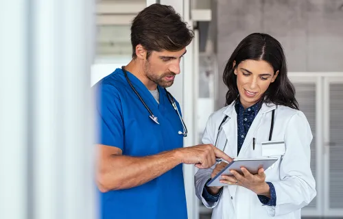 two health care professionals reviewing patient data on a tablet