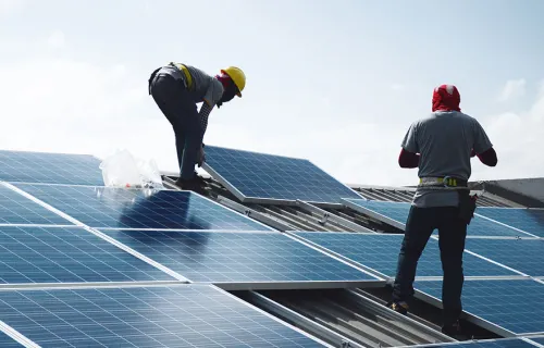 Zwei Männer legen Solarzellen aufs Dach