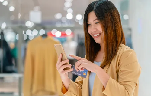 Woman with phone smiling in retail store