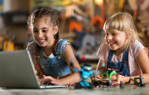 two girls smiling looking at a laptop