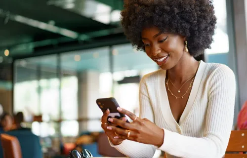 Kuvituskuva: hymyilevä nainen katsoo älypuhelintaan