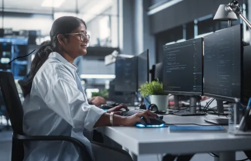 Woman working at dual mornitors in an office