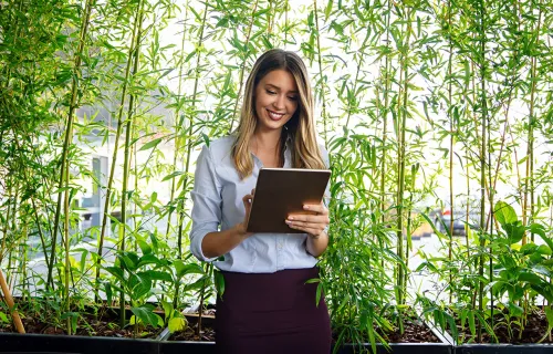 Woman on tablet in front of wall of bamboo