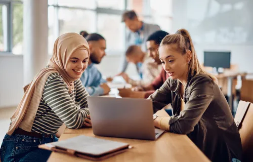 Young people looking at a laptop in a learning environment