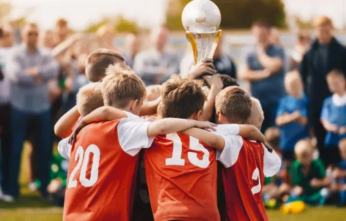 Youth soccer team huddled holding up a trophy