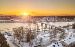 Vue aérienne de Joensuu (Finlande) couverte de neige avec le soleil se levant à l’horizon. 