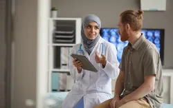 Male patient listening to his doctor while she telling about the disease using digital tablet they sitting on couch at hospital
