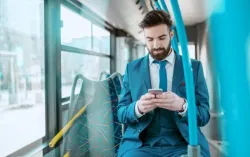 Ein junger Geschäftsmann, der im öffentlichen Bus sein Smartphone benutzt