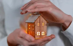 personne tenant une maquette lumineuse d'une maison en bois