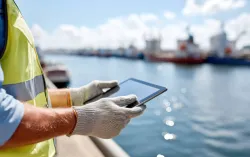 Utilities worker holding a tablet by a river