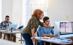 Colleagues reviewing work on a monitor at a desk