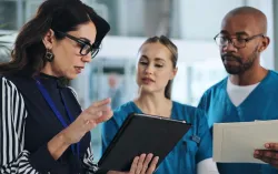 consultant discutant des données sur une tablette avec des professionnels de santé