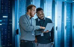 consultants in data center discussing information on laptop