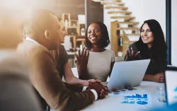 Consultants smile and discuss data on laptop