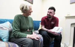 Delta Wellbeing worker talks to elderly care patient on sofa