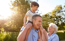 Elderly couple playing with child on shoulders