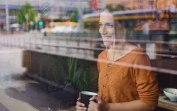 Person looking out of widow with cup in hand
