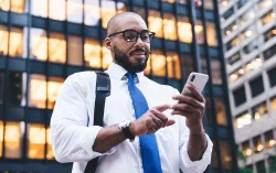 person using mobile phone in front of office building