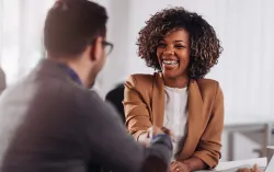 Two people smiling and shaking hands while seated