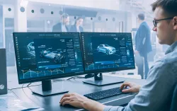 Männlicher Datenwissenschaftler betrachtet zwei Computerbildschirme in einer Autofabrik.