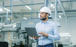 Male employee in fatory holding laptop 