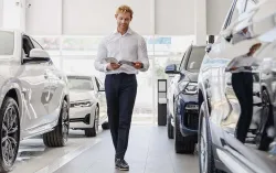 Man standing and reading magazine in car showroom