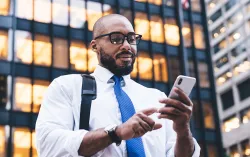 personne utilisant un téléphone portable devant un immeuble de bureaux